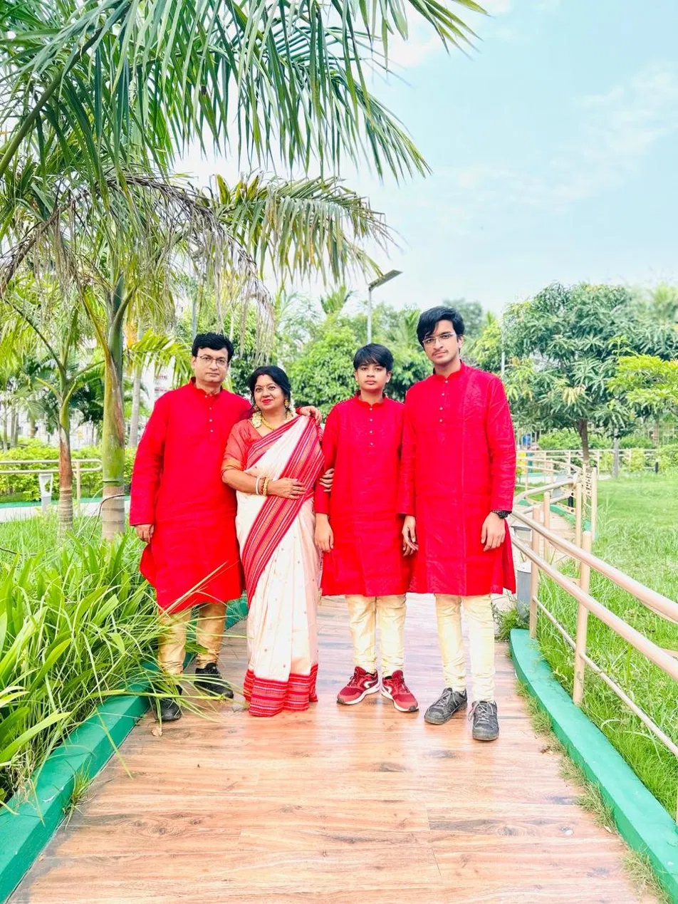 The Suhrid family band — Dolon Roy Ganguly with her husband and two sons, all in red, on a Newtown walkway